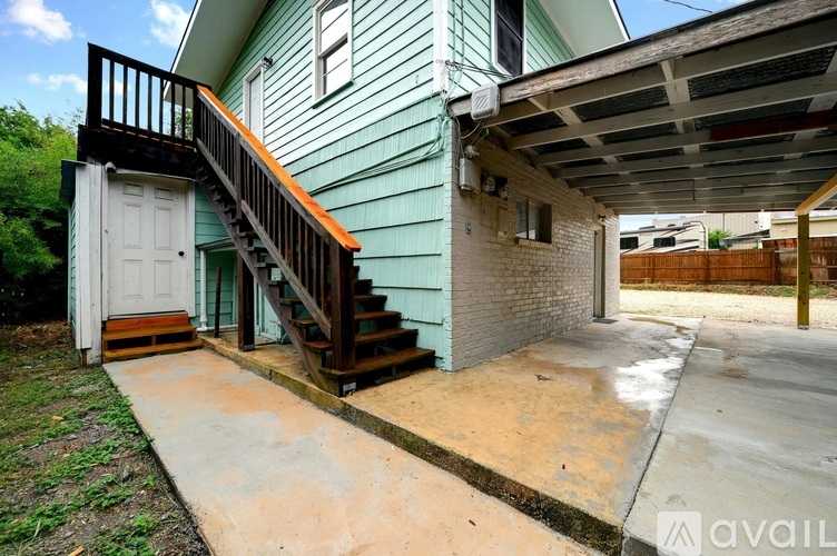 A house with a green exterior and a wooden staircase leading to a white door.