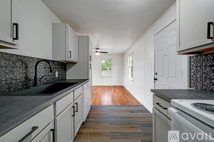 A kitchen with white cabinets and a wooden floor.