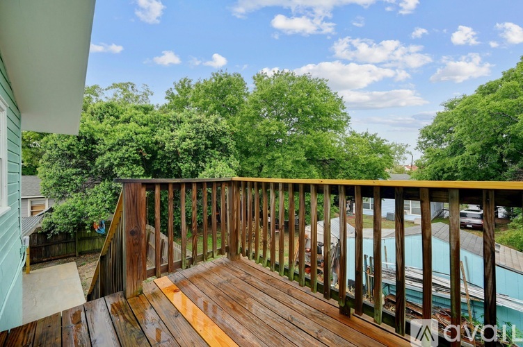 A wooden deck overlooks a pool and green trees.