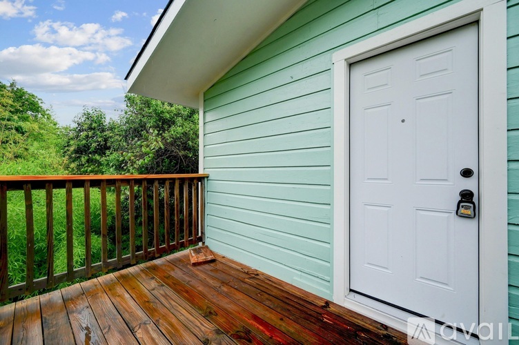 A white door with a black handle is on a green house.