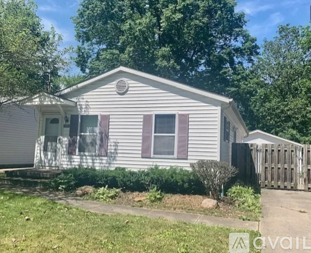 A house with a fence and a tree in front of it.