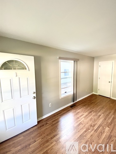 A room with a white door and a window with a view of a building outside.
