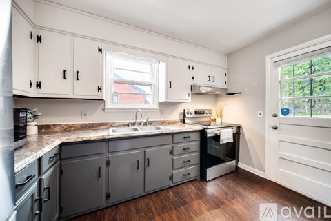 A kitchen with white cabinets and a window above the sink.