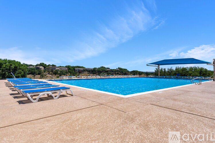A pool with blue loungers and a blue umbrella.