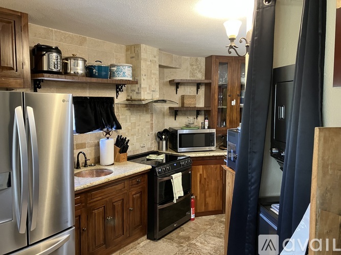 A kitchen with a stainless steel refrigerator and wooden cabinets.