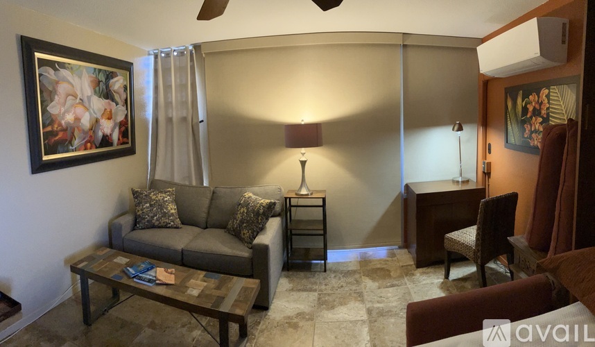 A living room with a grey couch, a coffee table, and a painting on the wall.