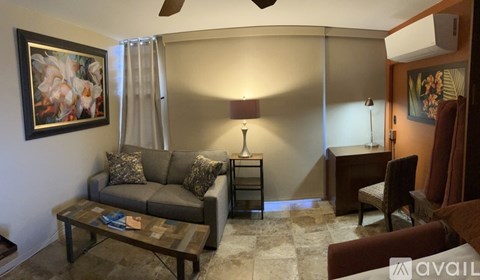 A living room with a grey couch, a coffee table, and a painting on the wall.