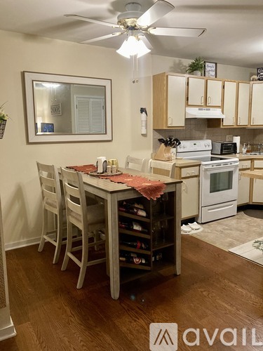 A kitchen with a table and chairs in the foreground and a stove top oven in the background.