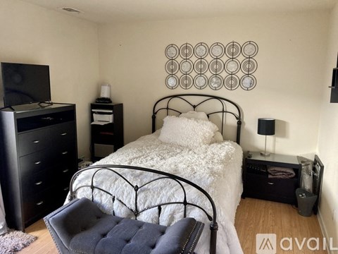 A bedroom with a bed, dresser, and a wall hanging.