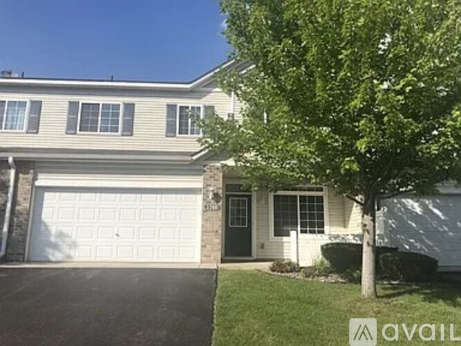 A house with a garage and a tree in front.