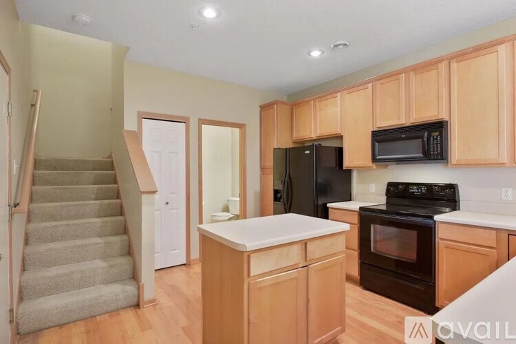 A kitchen with wooden cabinets and a black refrigerator.