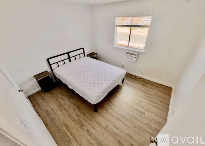 A bedroom with a bed, nightstand, and window.