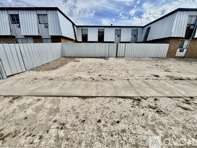 A large, empty lot with a fence and a building in the background.