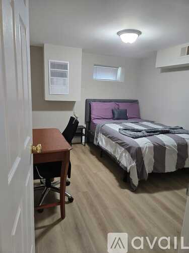 A bedroom with a bed, desk, and chair.