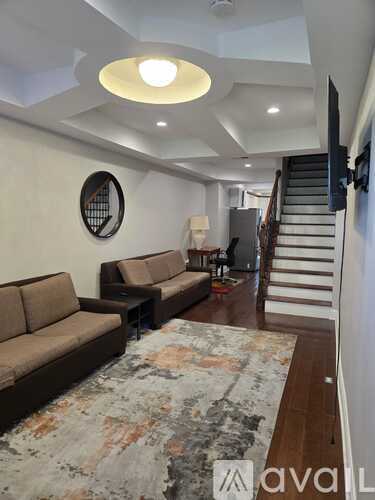 A living room with a brown sofa and a rug.