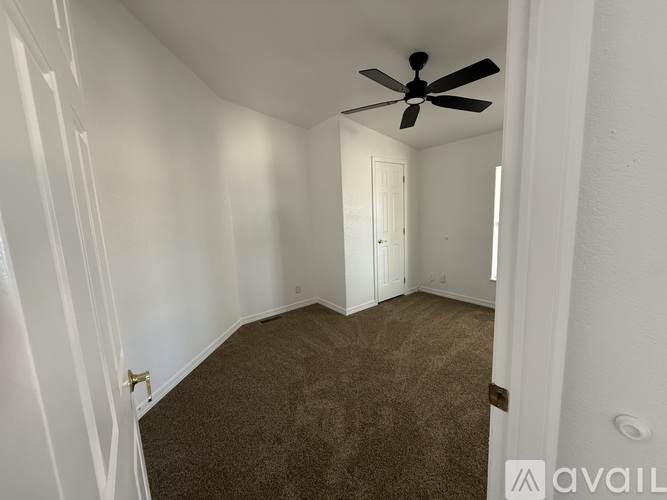 A room with a ceiling fan and carpeted floor.
