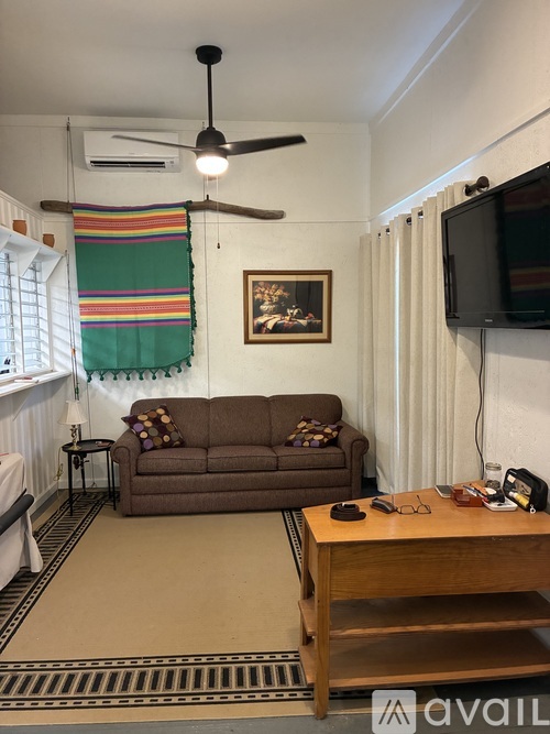 A living room with a brown couch, a wooden table, and a ceiling fan.