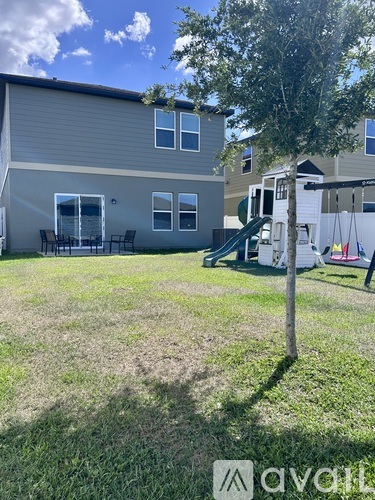 A tree stands in a yard in front of a house.