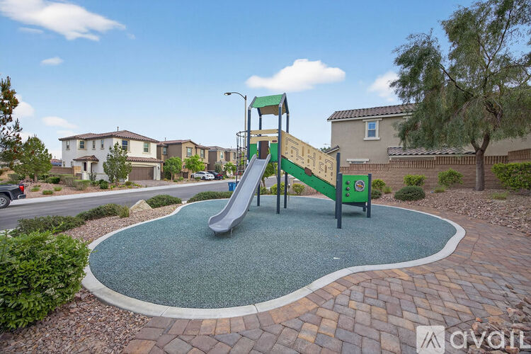 A playground with a green slide and a grey ground.