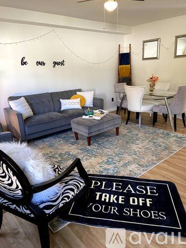 A living room with a sign on the floor that says "Please take off your shoes.".