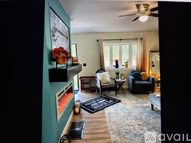 A living room with a black rug on the floor and a ceiling fan above.