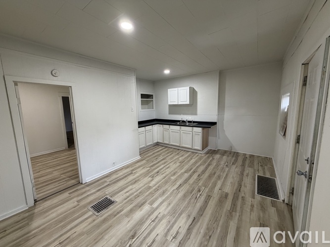A room with wooden flooring and white walls.