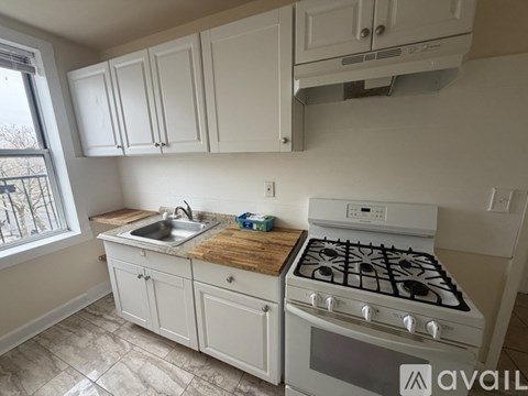 A kitchen with white cabinets and a white stove top oven.