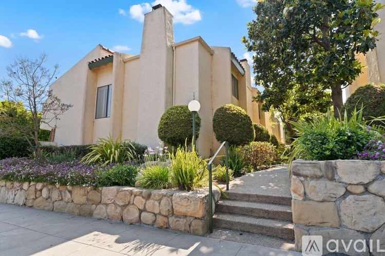 A house with a stone wall and a tree in front.