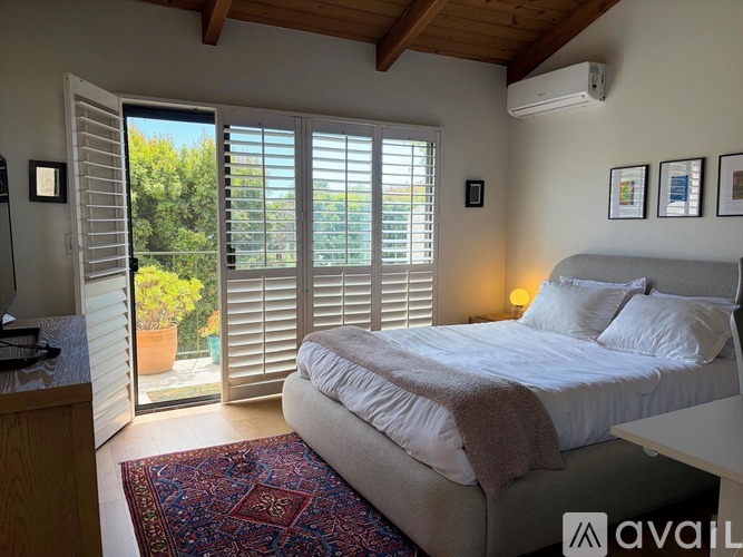 A bedroom with a large bed and a balcony with open shutters.