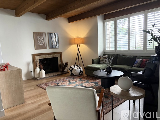 A living room with a fireplace, a chair, a table, and a vase.