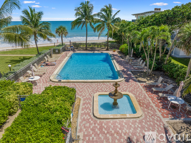 A pool surrounded by palm trees and a fountain in the middle.