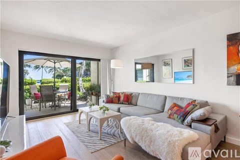A living room with a grey couch and a coffee table in front of a sliding glass door.