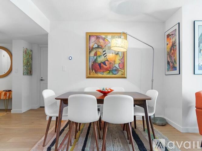 A dining room with a wooden table and white chairs.