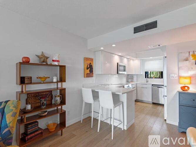 A kitchen with white chairs and a wooden shelf.