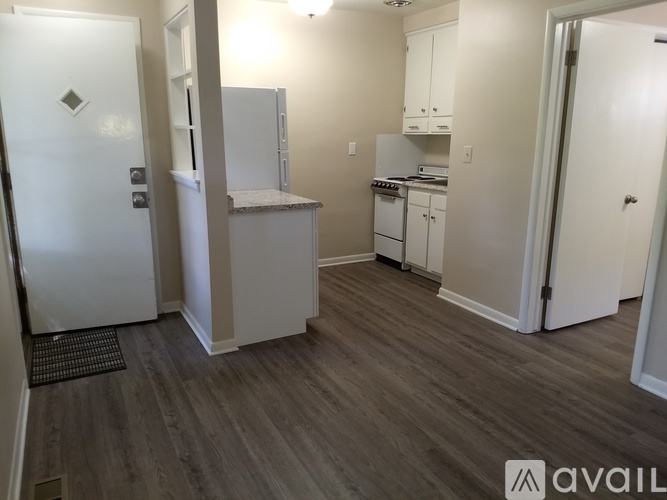 A kitchen with white appliances and cabinets in a room with wooden flooring.