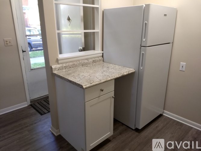 A kitchen with a marble countertop and a refrigerator.