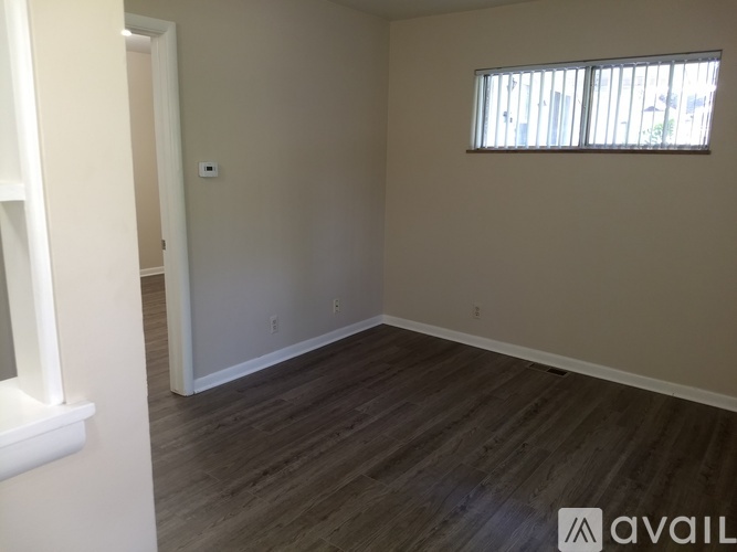 A room with wooden flooring and a window with blinds.