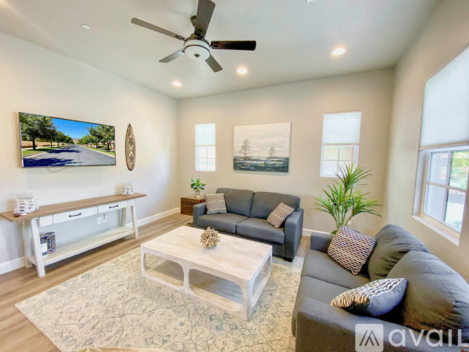 A living room with a grey couch, a white coffee table, and a painting of a road on the wall.