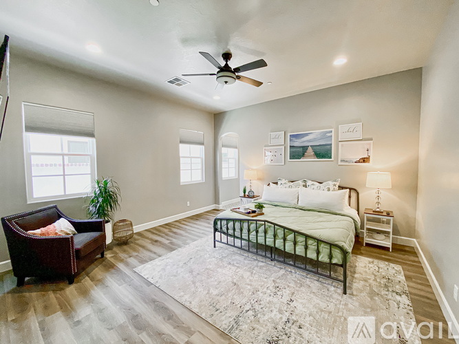 A bedroom with a bed, a chair, and a ceiling fan.