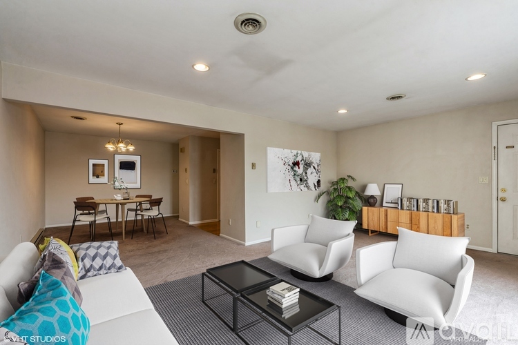 A living room with a white couch, a coffee table, and a dining table with chairs.
