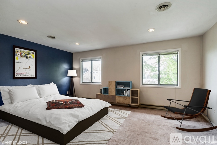 A bedroom with a bed, a chair, and a window.