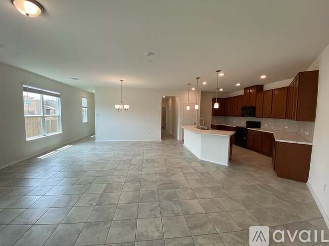 A spacious living room with a kitchen area in the background.