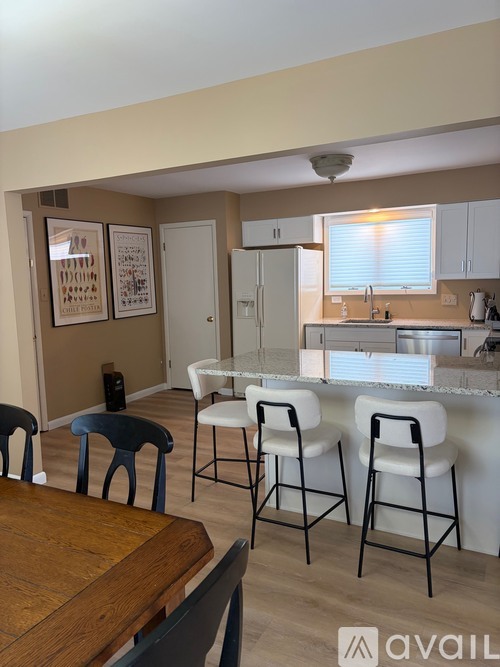 A kitchen with white chairs and a wooden table.