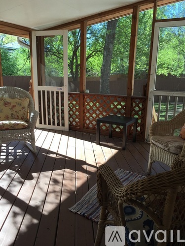 A sunny day on a wooden deck with a wicker chair and a patterned cushion.