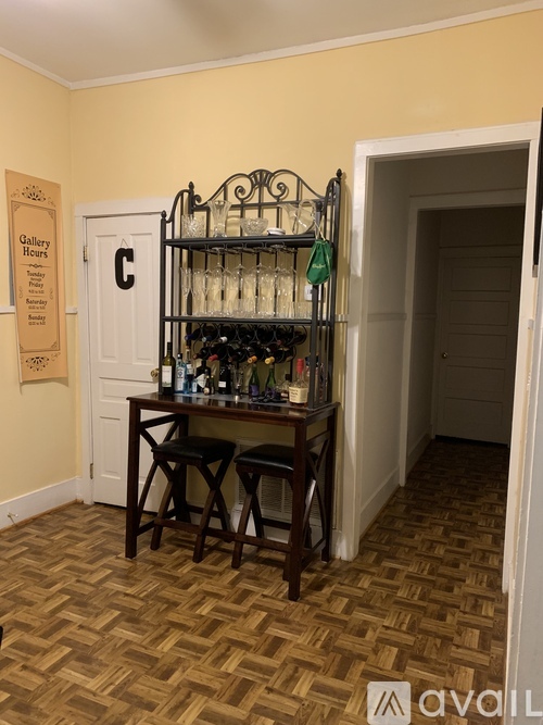 A room with a wooden floor and a shelf with glasses on it.