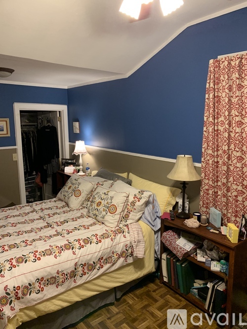 A bedroom with a bed, nightstand, and a window with curtains.