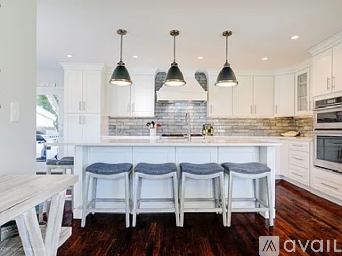 A kitchen with white cabinets and a brick backsplash.