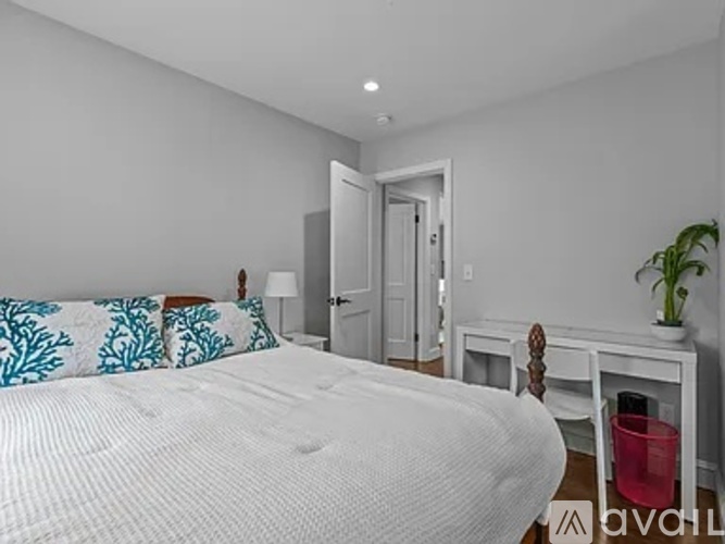 A bedroom with a white bed and a white chair.