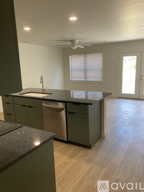 A kitchen with green cabinets and a black countertop.