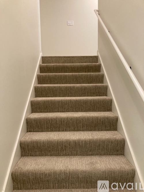 A set of stairs with a carpeted runner and white walls.